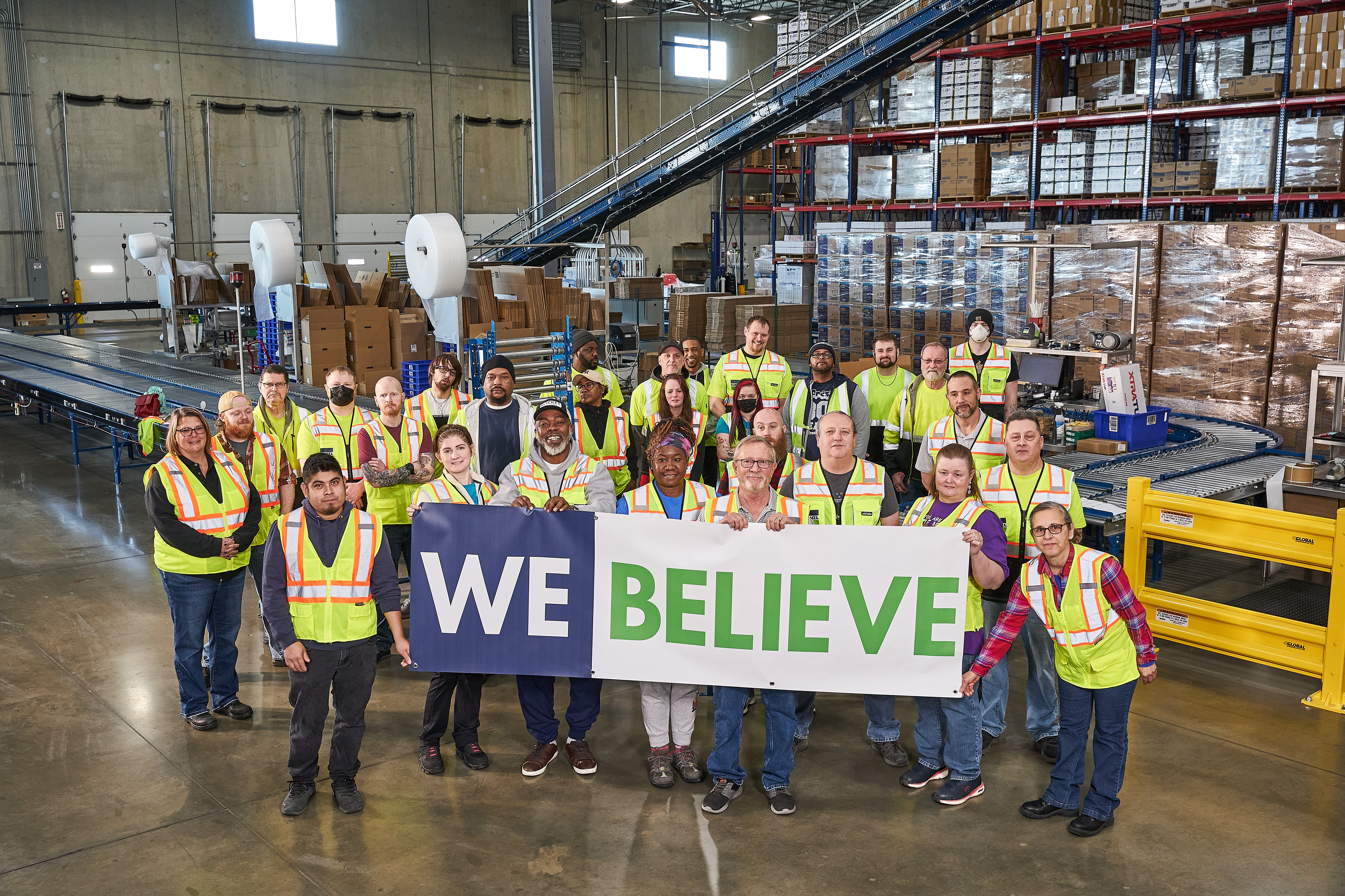 The Bunzl warehouse team displaying a We Believe banner in the warehouse at Koch Supplies in Missouri